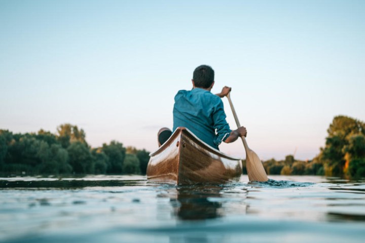 a man riding on the back of a boat in the water